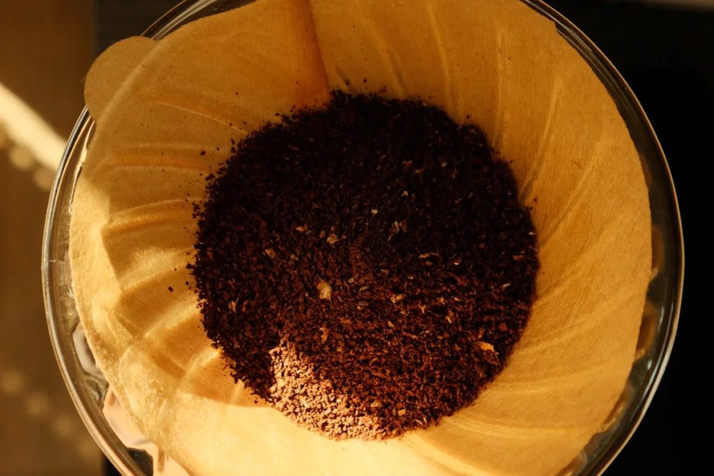 ガラスのドリッパーにセットした茶色いペーパーフィルターと、中に入れたコーヒーの粉を真上から見たところ