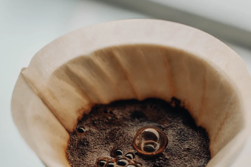 ドリッパーにセットした茶色いペーパーフィルターと、その中で泡が立つコーヒーの粉