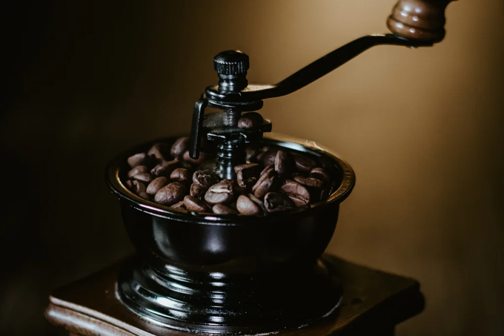 木の箱の上に、コーヒー豆の入った黒いホッパーとハンドルが付いた手挽きのコーヒーミル
