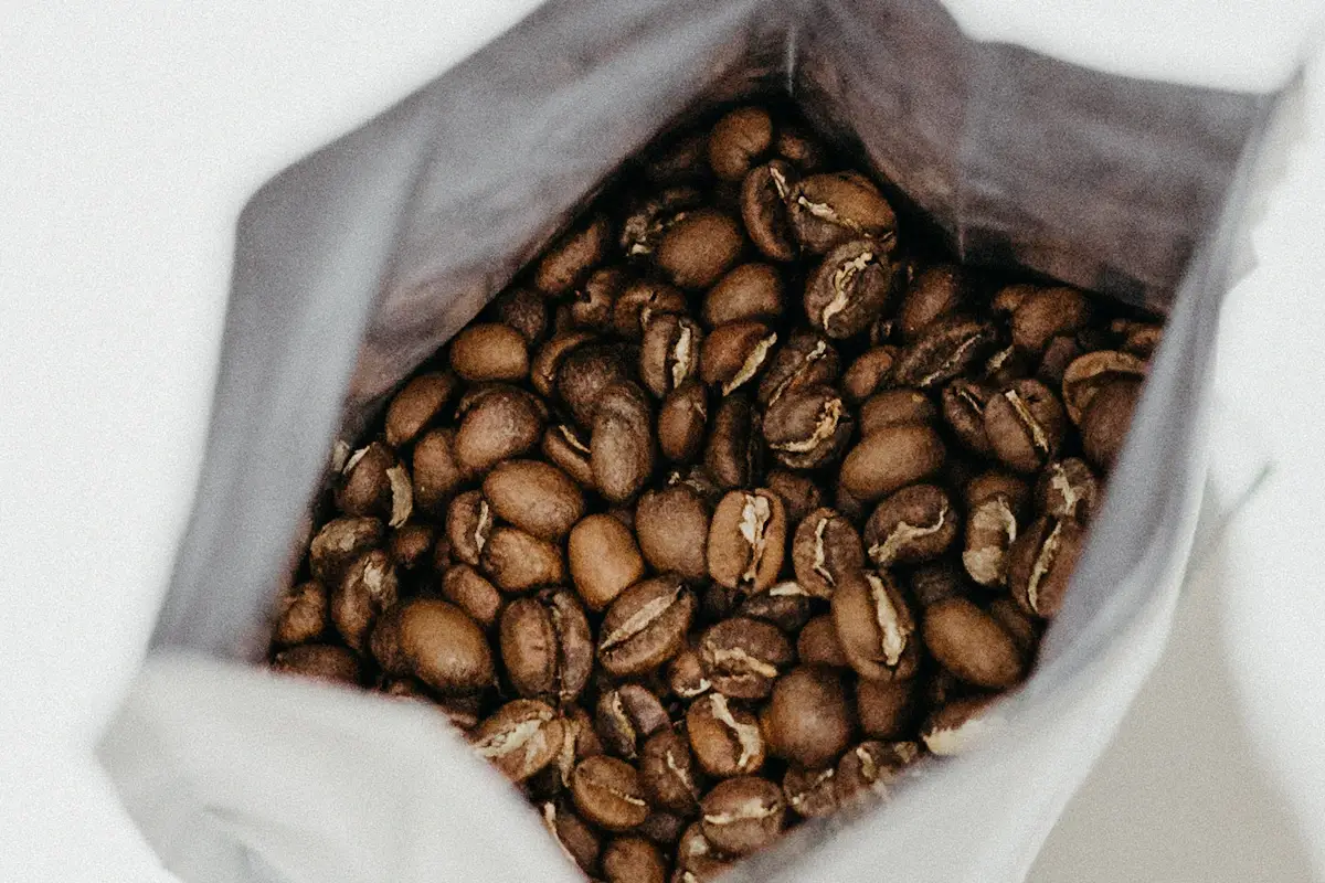 口を開けた白い袋に入った、焙煎したコーヒー豆