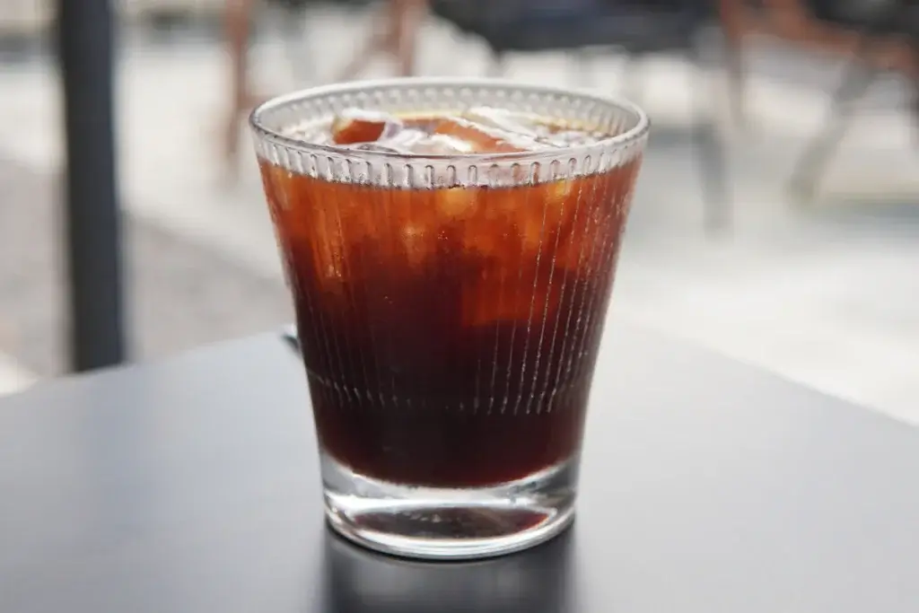 黒いテーブルに置いた、氷の入ったグラスのアイスコーヒー