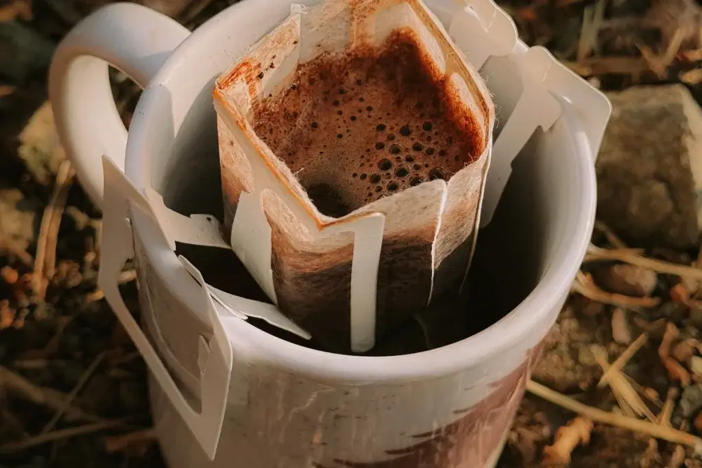 白いマグカップにかけたドリップバッグ。中には、お湯を注いだコーヒーがたまっている