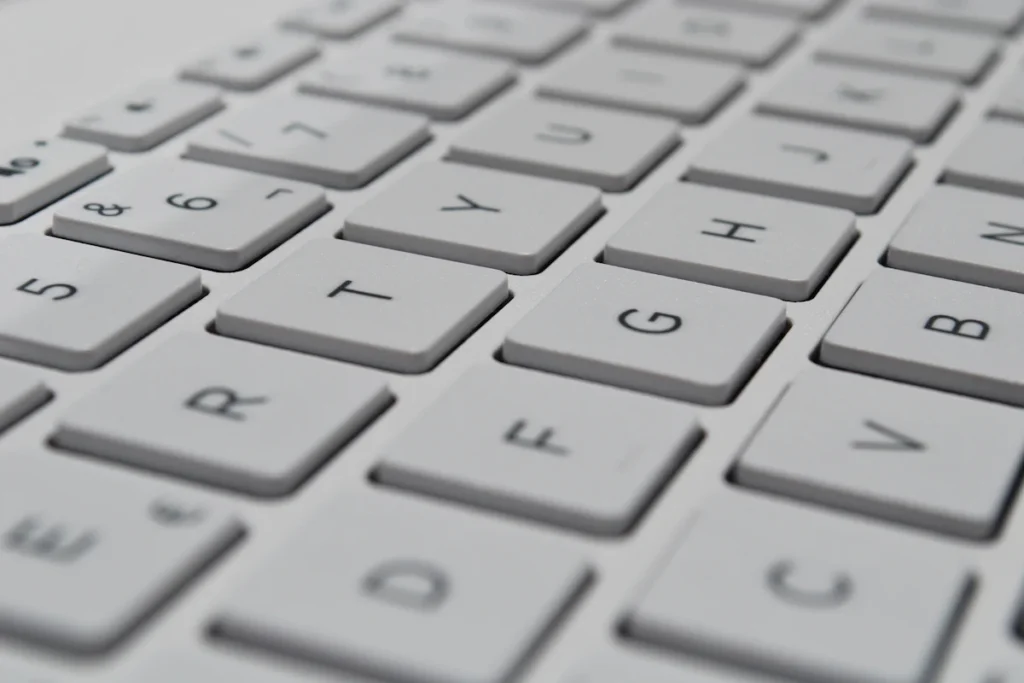 白いキーボードのキーを、斜めから近くで写した写真。キーにはアルファベットや数字が印字されている