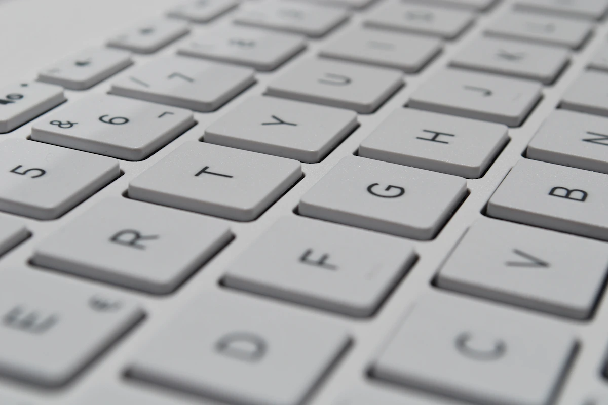 白いキーボードのキーを、斜めから近くで写した写真。キーにはアルファベットや数字が印字されている