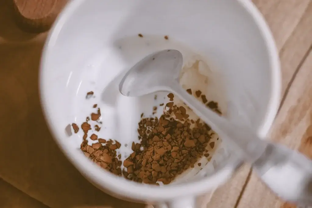白いマグカップの底に入れたインスタントコーヒーの粒と、スプーン